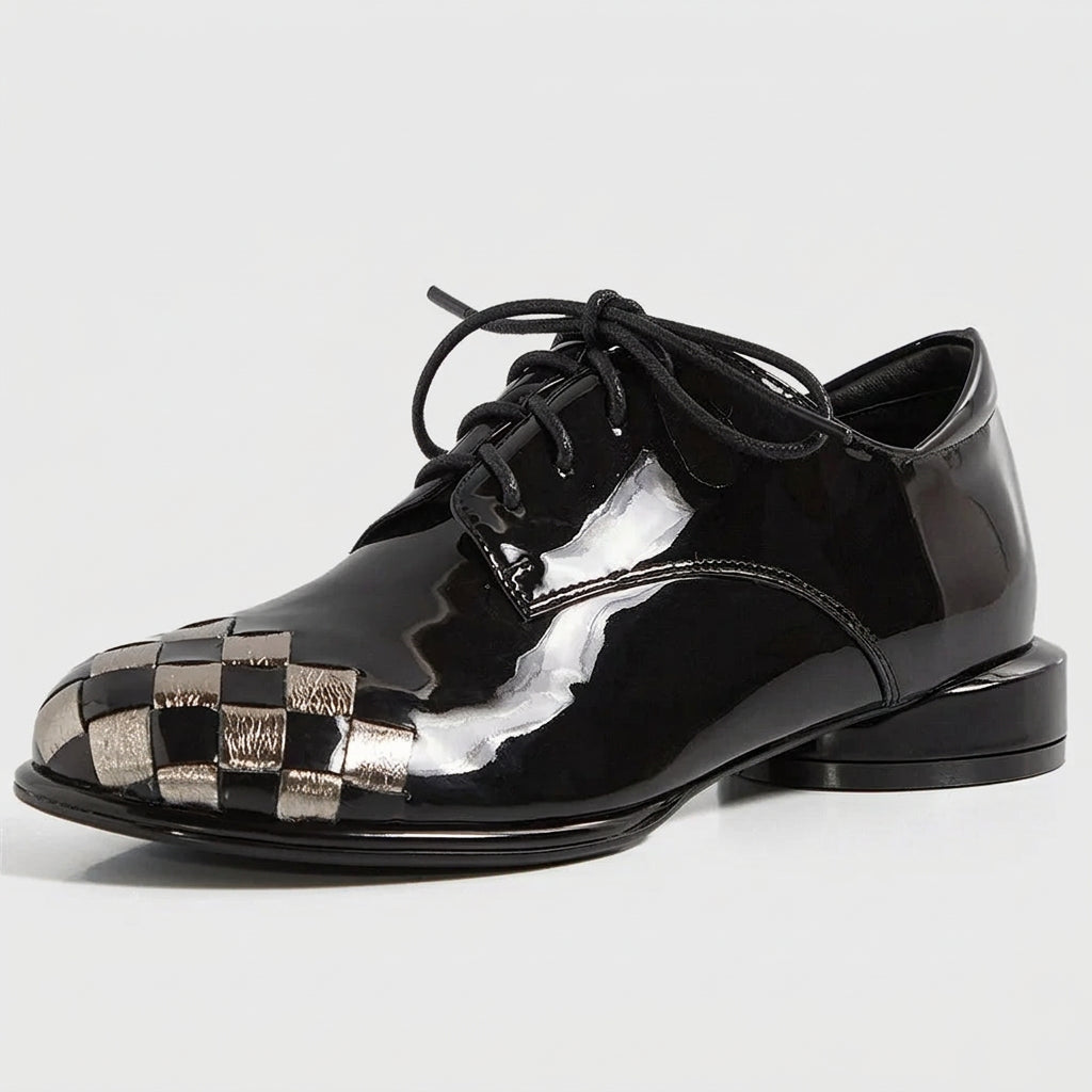 A glossy black patent leather lace-up shoe with a woven metallic silver and black checkerboard pattern on the toe cap, shown against a plain white background.