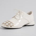 A glossy off-white patent leather lace-up shoe with a woven metallic gold and white patterned toe cap, shown on a plain white background.