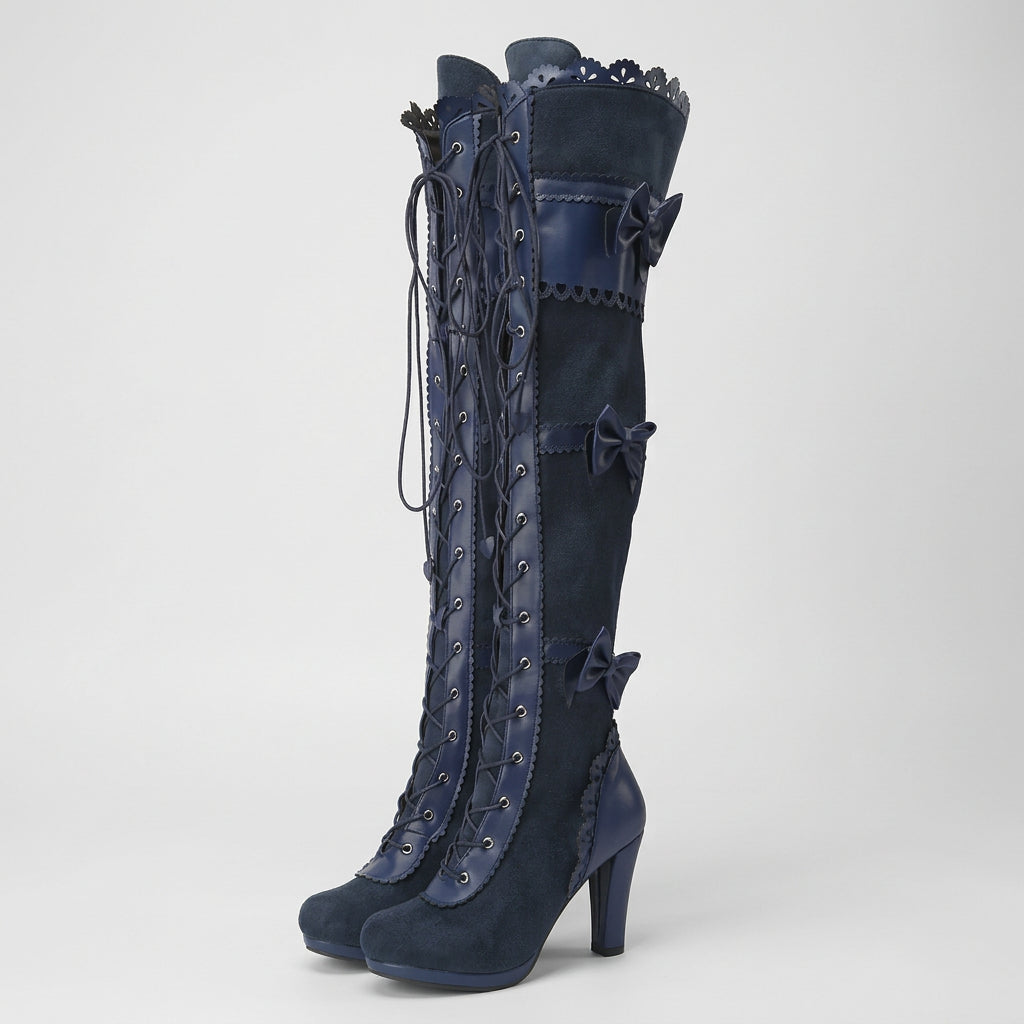 Pair of navy blue knee-high boots with decorative laces on a white background