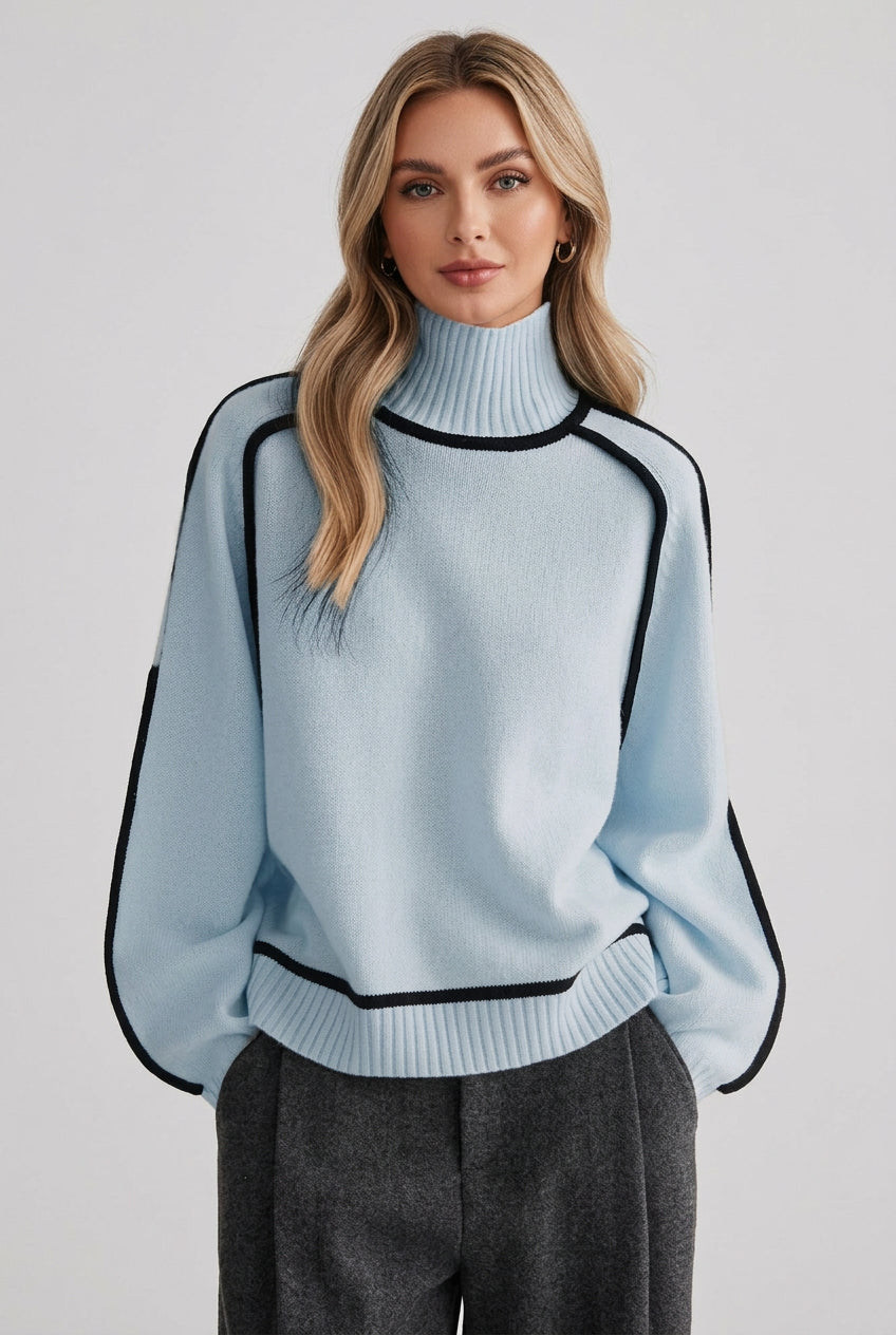 Light blue sweater with black accents worn by a person against a brick wall.