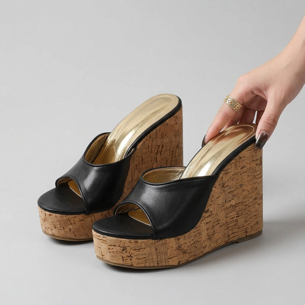Black open-toe wedge sandals with cork wedge on a dark surface.